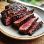 Close-up of perfectly cooked Alton Brown London broil, sliced to reveal a juicy pink center and a seared crust.
