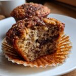Close-up of a delicious banana nut muffin, cut in half, revealing a moist interior and nutty topping.