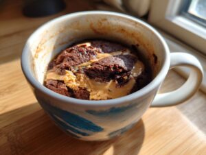 Close-up of a rich chocolate protein mug cake topped with creamy peanut butter.