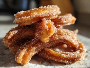 A close-up stack of freshly fried churros coated in cinnamon sugar.