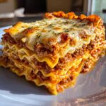 A mouthwatering slice of easy lasagna with ricotta, featuring layers of pasta, meat sauce, and melted cheese.