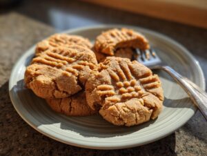 A close-up of several Easy Peanut Butter Cookies with classic fork marks on a light green plate.