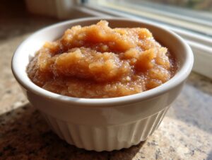 A close-up of a white ramekin filled with chunky, spiced homemade applesauce.