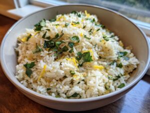 A close-up of a bowl filled with fluffy Mediterranean lemon rice, garnished with fresh parsley and lemon zest.