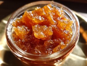 A close-up, top-down view of glistening homemade pear preserves filling a small glass jar.