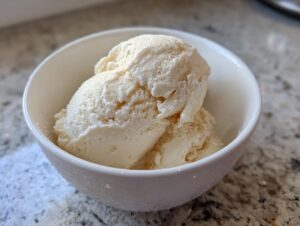 A white bowl filled with scoops of creamy, vanilla protein ice cream.