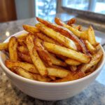 A white bowl overflowing with perfectly golden and seasoned air fryer french fries.
