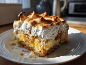 A delicious slice of authentic banana pudding with layers of vanilla custard, bananas, and graham cracker crust, topped with toasted meringue.