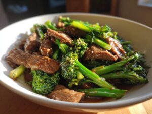 A close-up of a white bowl filled with tender slices of beef and vibrant green broccoli, coated in a savory sauce.