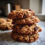 A stack of four delicious chewy oatmeal cookies with visible raisins and oats.