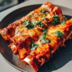 Close-up of three delicious chicken enchiladas topped with melted cheese and fresh cilantro.