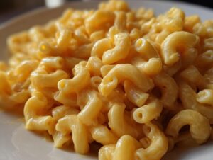 A close-up, mouthwatering shot of creamy vegan mac and cheese, showcasing the cheesy sauce coating the elbow macaroni.