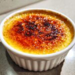 Close-up of a perfectly caramelized crème brûlée with a golden-brown, slightly charred sugar crust.
