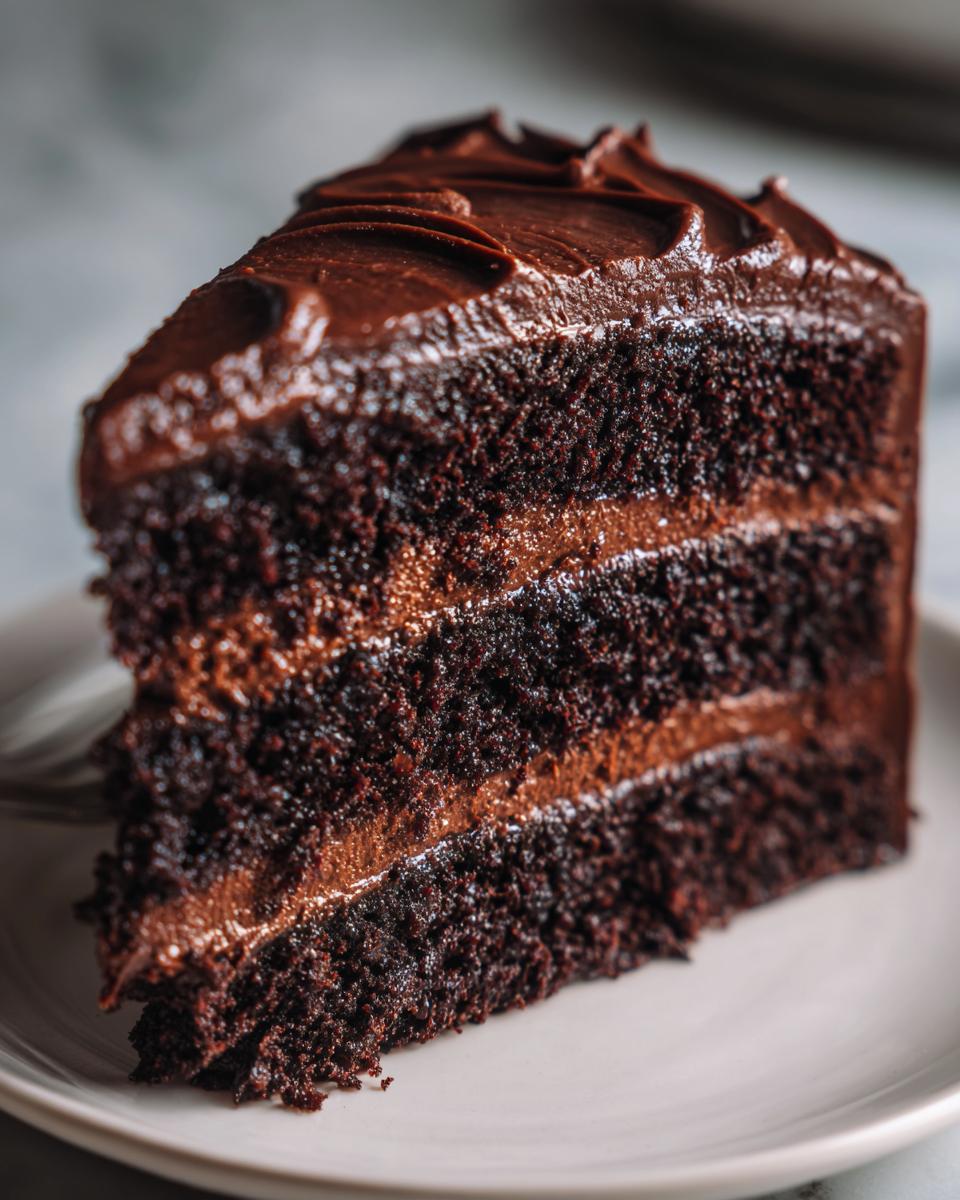 A moist, rich slice of decadent chocolate cake with layers of chocolate frosting.