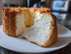 A slice of fluffy Angel food cake with a golden-brown crust, presented on a white plate.