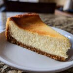 A perfect slice of dense and creamy New York cheesecake with a graham cracker crust.