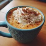 A close-up of a creamy Pumpkin Spice Latte topped with whipped cream and a sprinkle of cinnamon.