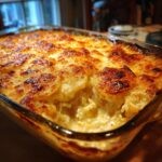 Close-up of bubbling, golden-brown scalloped potatoes fresh from the oven in a glass baking dish.