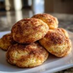 A close-up shot of a pile of five freshly baked Snickerdoodles, coated in cinnamon sugar.