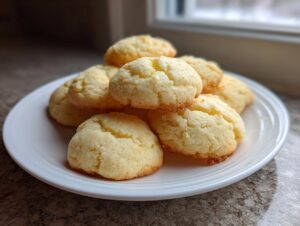 A stack of golden, crumbly 4-ingredient butter cookie treats piled high on a white plate near a window.