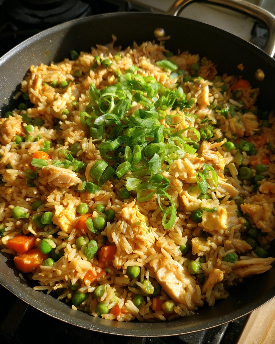 Close-up of freshly made Chicken Fried Rice in a pan, topped with chopped green onions.