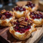 Close-up of delicious Cranberry brie bites in flaky phyllo cups topped with cranberry sauce and pecans.