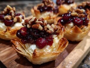 Close-up of baked Cranberry brie bites featuring creamy brie, cranberry topping, and pecans in crispy phyllo cups.