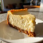 A delicious slice of creamy eggnog cheesecake with a graham cracker crust on a white plate.