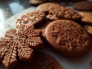 Close-up of freshly baked chewy gingerbread cookies, some shaped like snowflakes, with intricate embossed patterns.