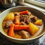 A close-up bowl of Instant Pot beef stew featuring tender beef chunks, carrots, and potatoes in a rich broth.