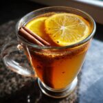 A warm glass of mulled cider, garnished with orange slices and cinnamon sticks.