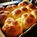 A close-up, overhead view of freshly baked Parker House rolls in a baking pan, golden brown and fluffy.