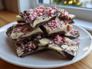 A stack of rich dark and white chocolate peppermint bark pieces, generously topped with crushed candy canes.