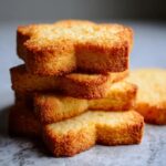 A close-up stack of perfectly baked, golden-brown sugar cookies in a star shape.