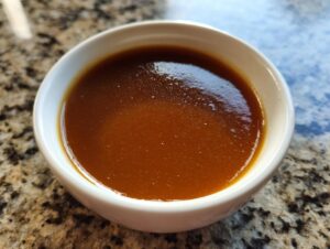 A close-up shot of rich, silky smooth turkey gravy in a white bowl, ready to be served.