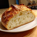 Cross-section of homemade yeast bread showing an open, airy crumb and dark, crusty top.