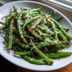 Close-up of roasted green beans topped generously with grated Parmesan cheese.