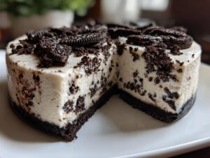 A rich, creamy slice of no-bake oreo cheesecake showing dark cookie pieces throughout the filling and topping.