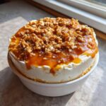 Rich, creamy dessert topped with caramel sauce and crunchy nuts, resembling a decadent apple dip.