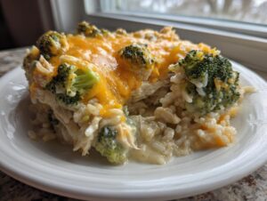 A close-up serving of creamy chicken broccoli rice casserole topped with melted cheddar cheese.