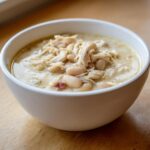 Close-up of a white bowl filled with creamy instant pot white chicken chili, featuring shredded chicken and white beans.