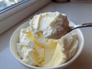 A spoonful of incredibly creamy slow cooker mashed potatoes being lifted from a white bowl.