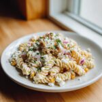 A serving of creamy street corn pasta salad made with rotini pasta, corn, red onion, and topped with crumbled cheese.