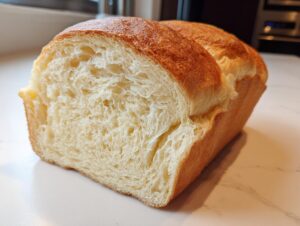 A close-up of a freshly baked loaf of japanese milk bread, showing its incredibly soft, white, and fluffy interior crumb.