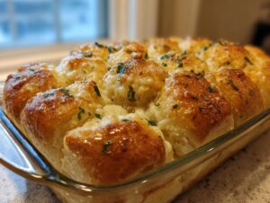Close-up of cheesy Hawaiian roll garlic bread baked in a glass dish, topped with melted cheese and parsley.