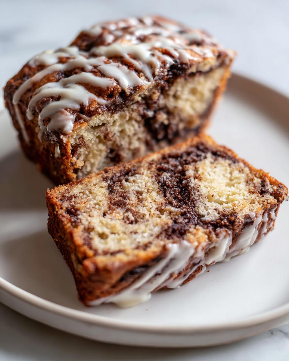 A slice of marbled apple bread with a rich cinnamon swirl and topped with a white vanilla glaze.