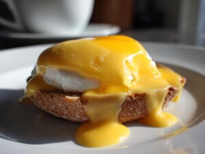 A perfectly poached egg on toast smothered in rich, yellow hollandaise sauce, ready to eat.
