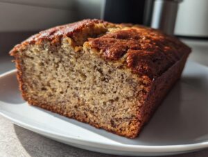 A close-up of a freshly baked slice of sugar free banana bread showing its moist crumb and dark crust.