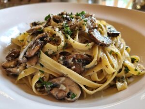 A close-up shot of creamy fettuccine mushroom pasta topped with sautéed mushrooms and fresh parsley.