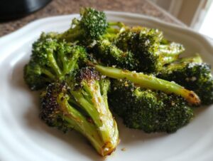 Close-up of perfectly roasted broccoli florets seasoned with salt on a white plate.